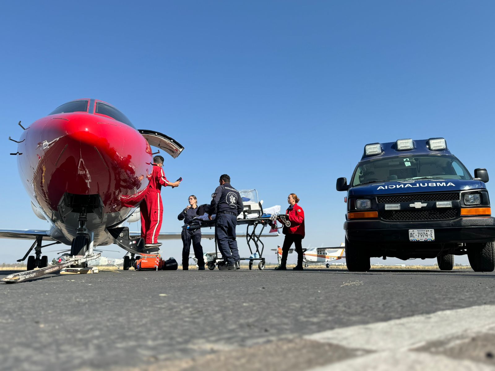 Equipo Mattsa con camilla junto a una aeronave y ambulancia en aeropuerto